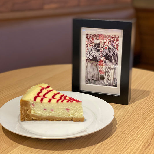Tableau décoratif représentant un vieux couple marocain portant deux bouquets de fleurs, sur un fond de zellige marocain rouges, encadré dans un cadre noir - Format A5.