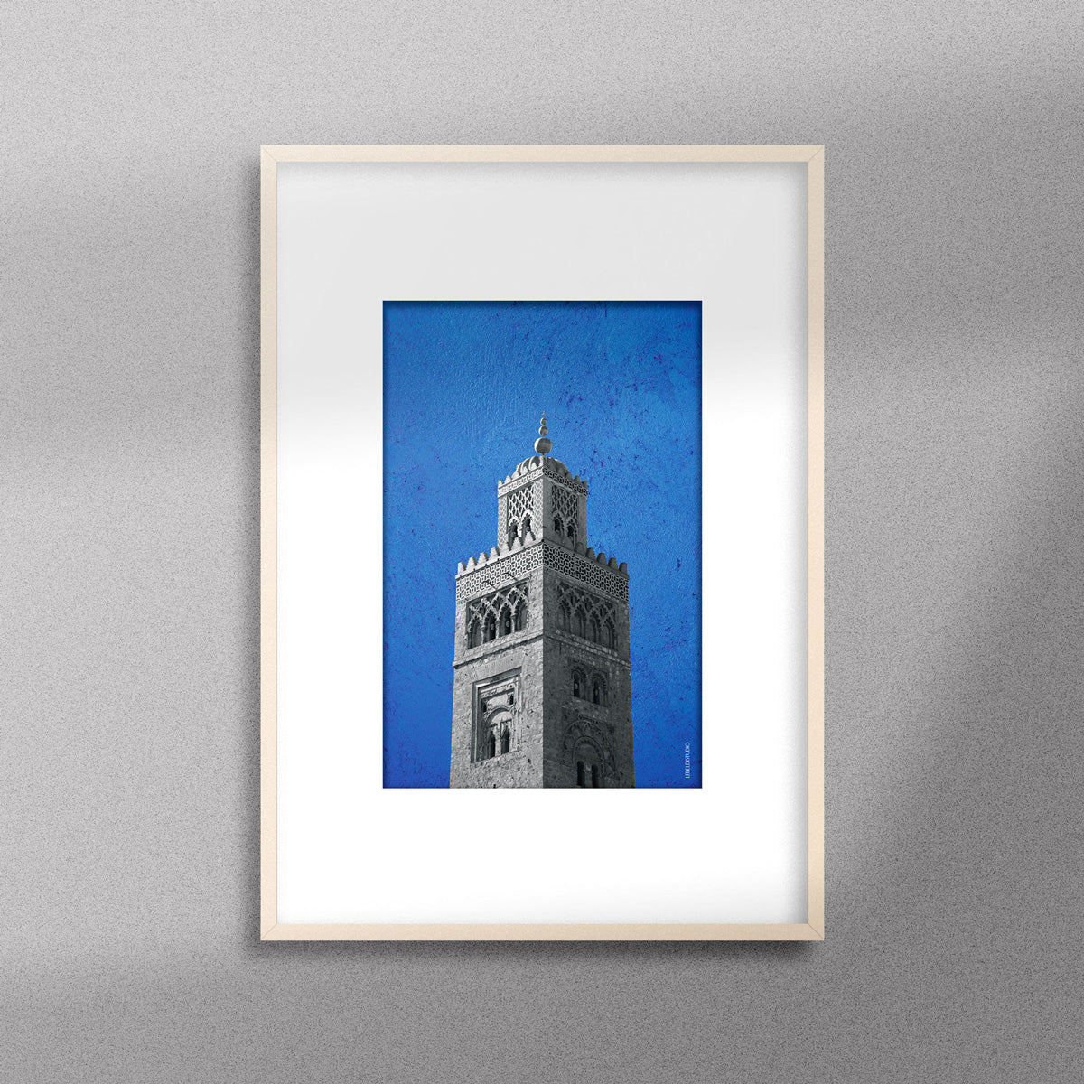 Tableau décoratif représentant la Koutoubia de Marrakech sur un fond bleu, encadré dans un cadre en bois - Format A4.