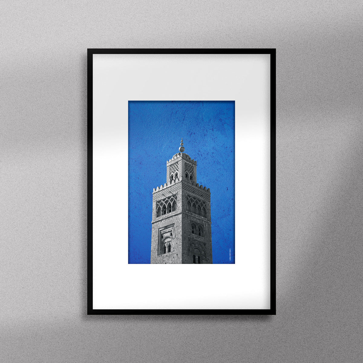 Tableau décoratif représentant la Koutoubia de Marrakech sur un fond bleu, encadré dans un cadre noir - Format A4.