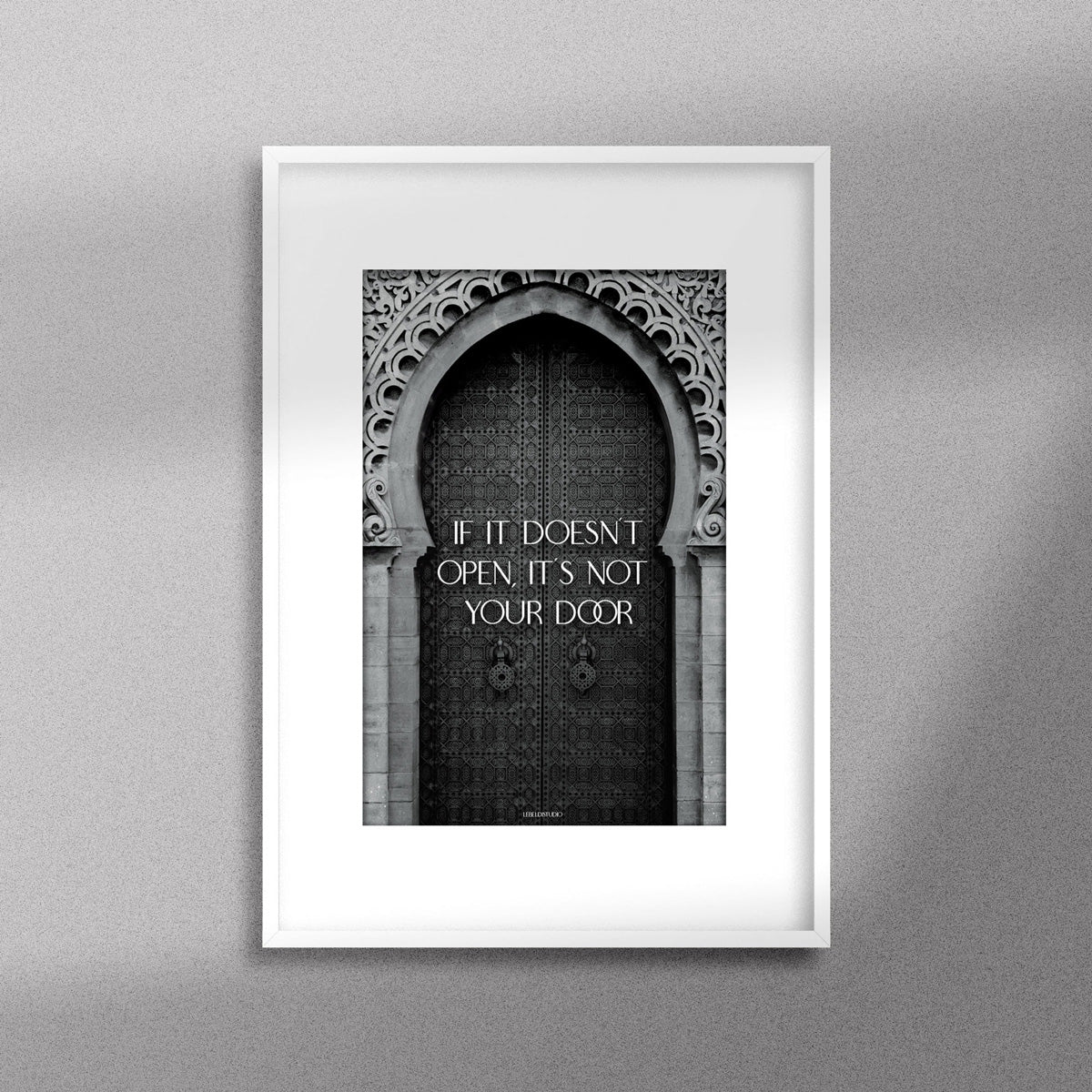 Tableau décoratif en noir et blanc d'une porte marocaine, avec la citation motivante : "If it doesn’t open it’s not your door", encadré dans un cadre blanc - Format A3.