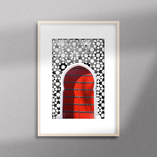 Tableau décoratif d'une porte marocaine en rouge, sur un fond de zellige marocain en noir et blanc, encadré dans un cadre en bois - Format A3