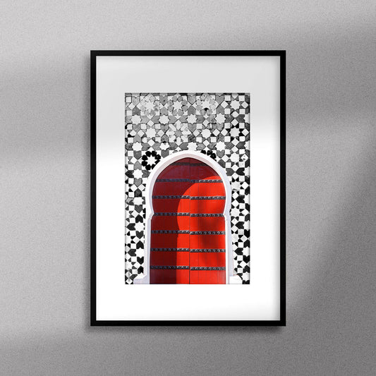 Tableau décoratif d'une porte marocaine en rouge, sur un fond de zellige marocain en noir et blanc, encadré dans un cadre en noir - Format A3
