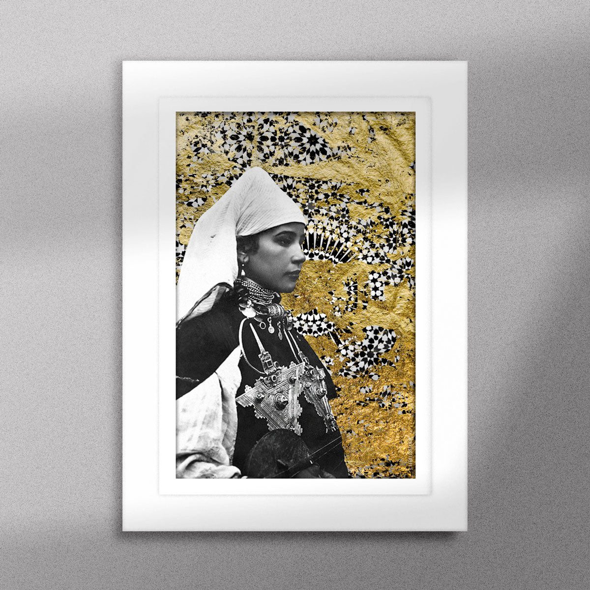 Tableau décoratif représentant un portrait d'une femme amazighe portant la fibule sur un fond de zellige marocain avec des feuilles d'or, encadré dans un cadre blanc - Format A5.