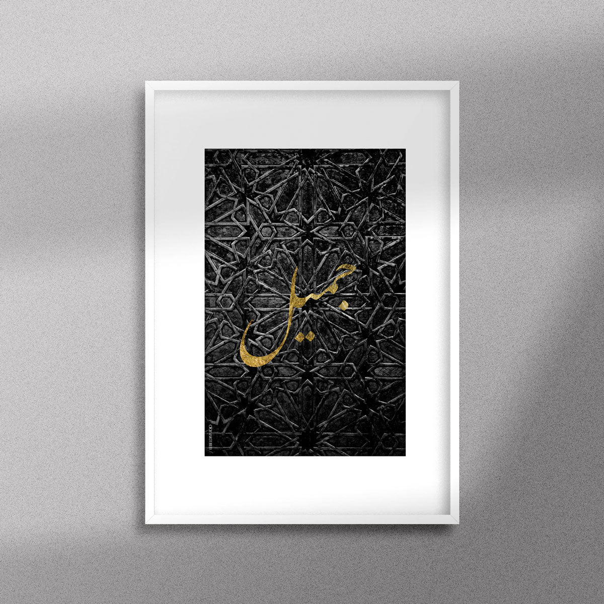 Tableau décoratif avec le mot "Jamil" qui signifie "beau" en doré sur un fond noir de motif artisanal marocain, encadré dans un cadre en blanc.