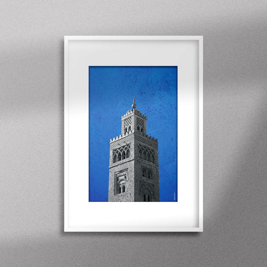 Tableau décoratif représentant la Koutoubia de Marrakech sur un fond bleu, encadré dans un cadre blanc - Format A3.