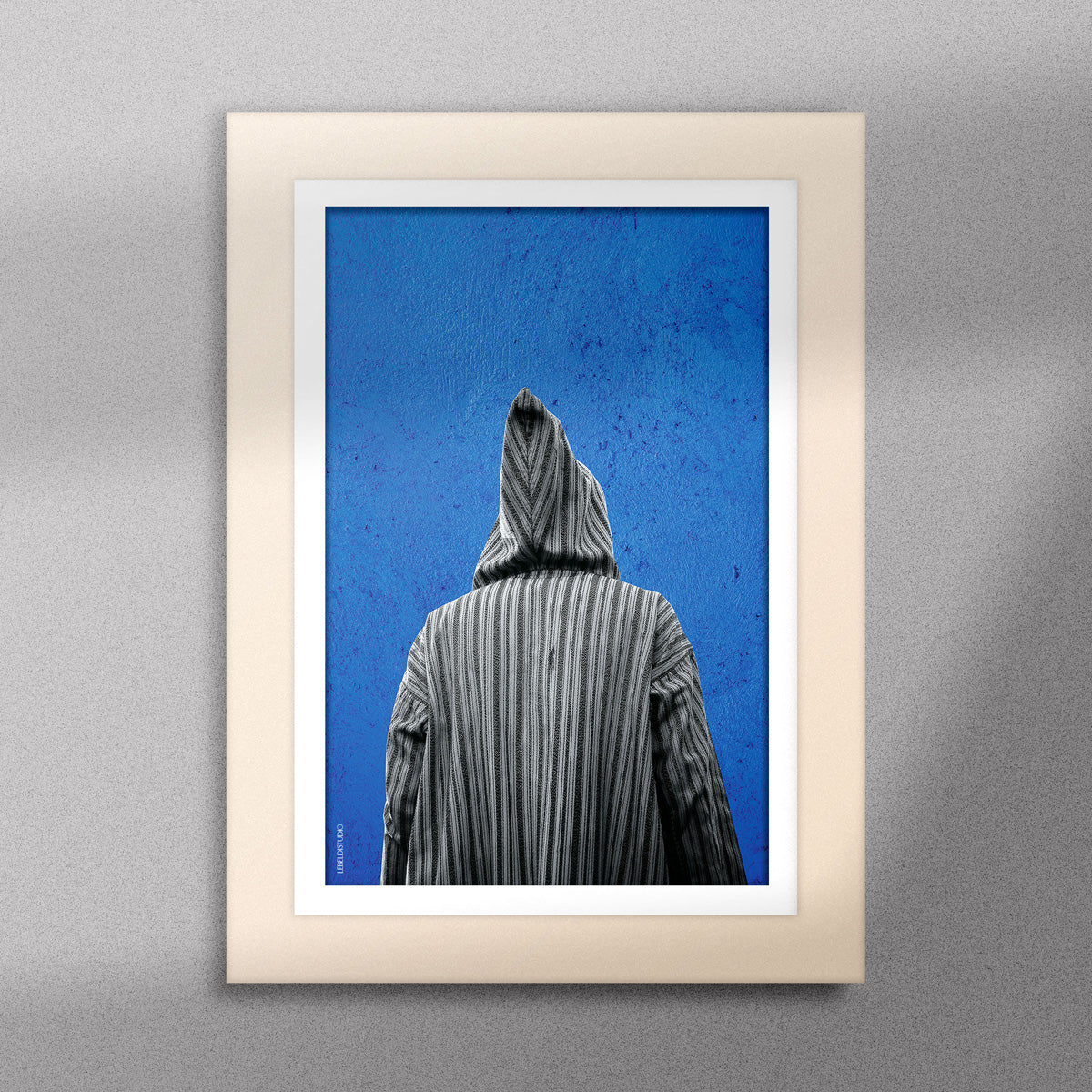 Tableau décoratif représentant un homme portant une djellaba marocaine sur un fond bleu d'un mur peint à la main, encadré dans un cadre en bois - Format A5.